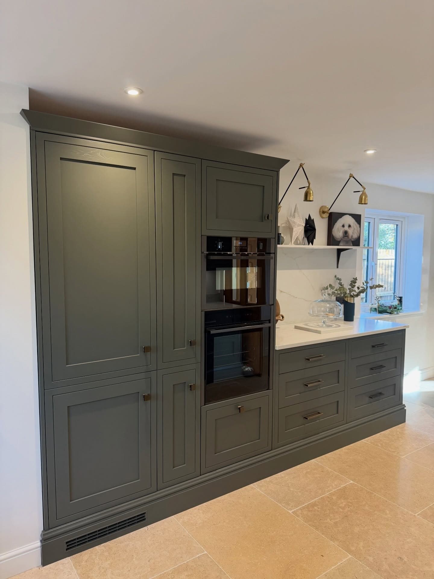 Tall in-frame larder units with integrated ovens and brass handles