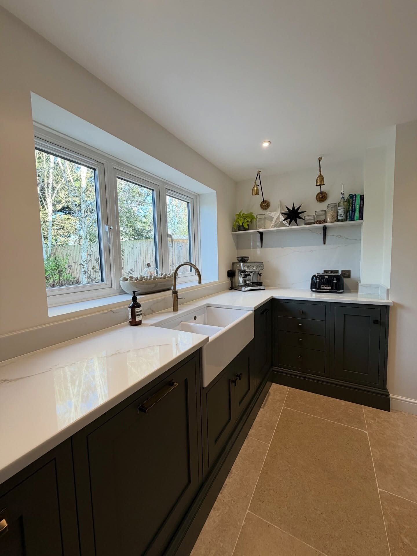 Dark shaker kitchen with a Belfast sink, quartz worktops and limestone floor