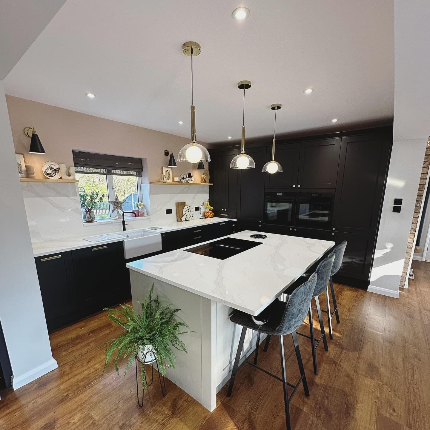 Dark shaker kitchen with a white quartz island, bar stools and brass pendant lights